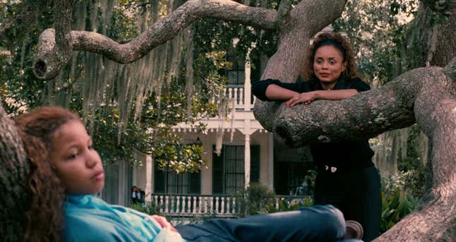 An older woman looks at a child lounging in a tree.