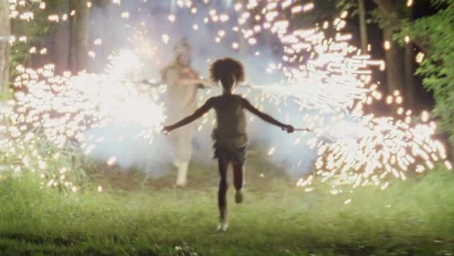 A girl runs while holding sparklers.